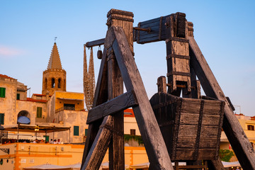 Alghero, Sardinia, Italy - Summer sunset view of the Alghero old town quarter with historic defense walls, fortifications and catapult construction - obrazy, fototapety, plakaty