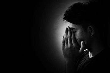 Depress and Hopeless boy praying in the dark in white tone