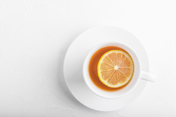 White cup with saucer with tea and lemon on white background. Copy space