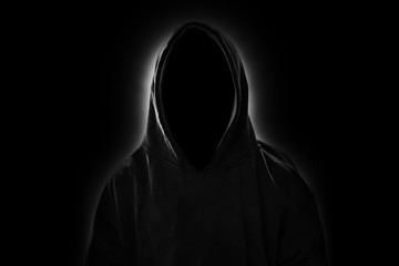 Man with hood in the dark with light shining behind, invisible man or hacker concept - obrazy, fototapety, plakaty