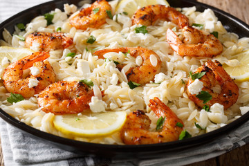 Mediterranean food Pasta orzo with grilled shrimps, feta cheese and lemon close-up on a plate. horizontal
