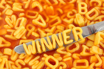 Alphabet spaghetti spelling winner with random letters in tomato sauce background