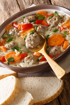Italian wedding soup with orzo pasta, meatballs and vegetables close-up. vertical