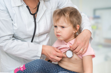 Pediatrician doctor examining a little girl by stethoscope
