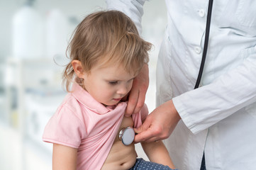 Obraz na płótnie Canvas Pediatrician doctor examining a little girl by stethoscope
