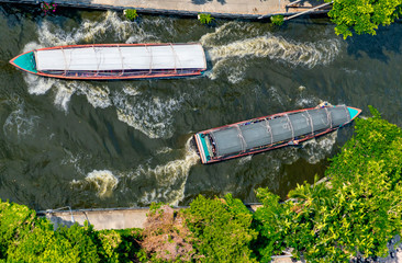 Arial view of two water buses passing each other on a canal in Bangkok.
