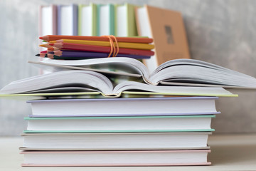 pencils and a stack of books on a white table on a concrete background