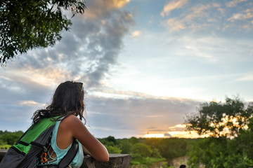 Travelling girl enjoying view to beautiful rural scenery after sunset. Happy woman looking at horizon in countryside.