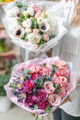 Two beautiful fresh cut bouquet of mixed flowers in woman hand. the work of the florist at a flower shop. Delicate Pastel tones color