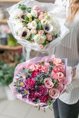 Two beautiful fresh cut bouquet of mixed flowers in woman hand. the work of the florist at a flower shop. Delicate Pastel tones color