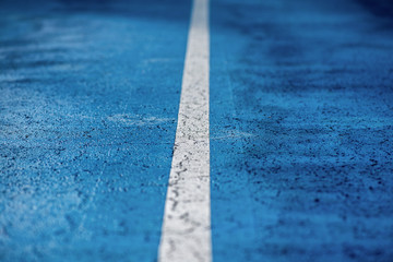 Fototapeta premium Abstract, blue background of newly made outdoor basketball court in park. Visible asphalt texture, freshly painted lines. 