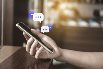 Women hand using smartphone typing, chatting conversation in chat box icons pop up. Social media maketing concept.