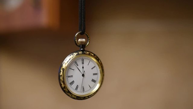 vintage pocket watch suspended on a cord swinging like a pendulum
