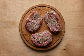 Three slices of raw meat on round cutting board