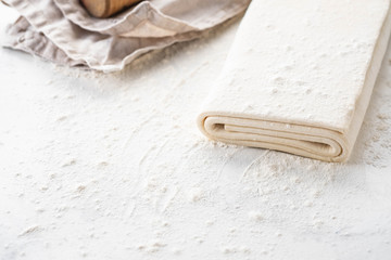Homemade raw puff pastry on a white background.