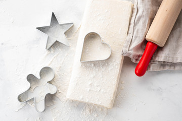 Raw puff pastry dough lies on a white table. Figures for baking cut metal mold. Copy space, top view.