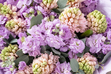 Bouquets of pink hyacinths and matthiola of lilac color in vase on wooden table. Spring flowers from Dutch gardener. Concept of a florist in a flower shop. Wallpaper.