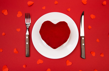 Heart on a plate for dinner. A romantic evening with hearts on red background.