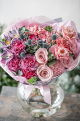 beautiful fresh cut bouquet of mixed flowers in vase on wooden table. . the work of the florist at a flower shop. Delicate Pastel tones color