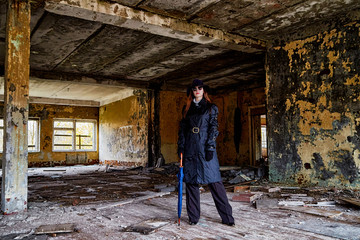 Obraz na płótnie Canvas Girl in a black cloak and hat posing in an abandoned, ruined house. Unusual photo shoot