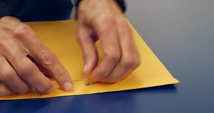 Close up on hands opening an orange envelope with important document inside after being mailed and delivered SLIDE LEFT.
