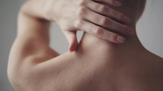 slender body of a girl close-up. a young woman touches her skin on her neck and shoulders.