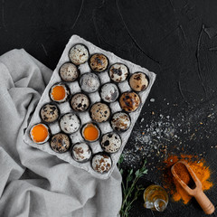 quail eggs with olive oil and spices on dark background.Top view.