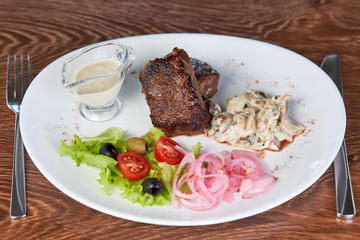 Beef medallions with mushrooms, lettuce, olives, cherry tomatoes and onions, close up, flat lay, top view