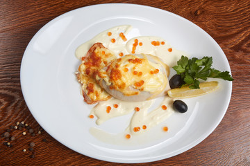 squid stuffed with cheese and baked flounder, decorated with white sauce and red caviar, next to a slice of lemon, cilantro and black olives, near the plate black, white, green and Brazilian pepper