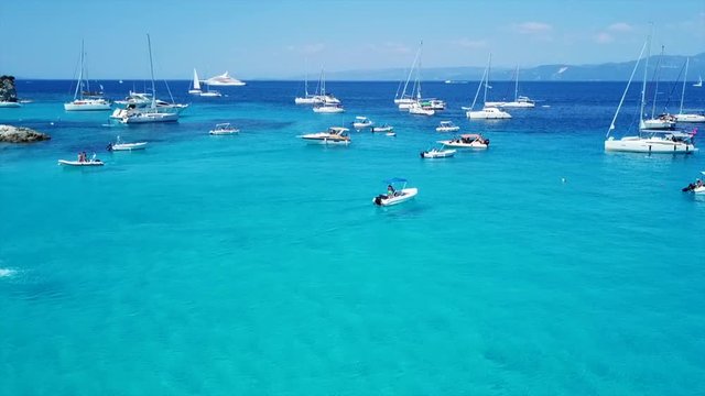 Aerial drone video of tropical paradise turquoise beach of Voutoumi with sail boats docked in island of Antipaxos, Ionian, Greece