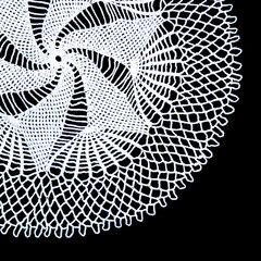 A part of isolated crocheted white doily with a pattern of spiral and fans on a black background. Round decorative doily