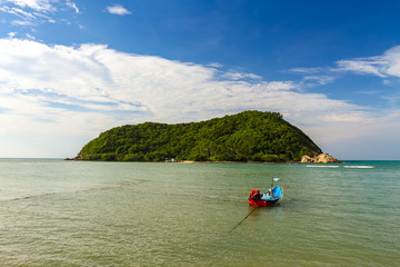 Fototapeta na wymiar Small fishing boat in front of a small tropical island in Indian ocean in Koh Phangan, Thailand. Beautiful view of azure sea and blue sky.
