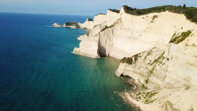 Aerial drone video of iconic white rock steep cliff volcanic bay of Cape Drastis and Peroulades area with tropical deep turquoise clear sea, Corfu island, Ionian, Greece