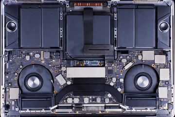 Disassembled laptop with two fans and a battery in an aluminum case. General view