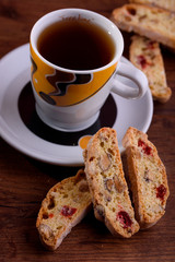 Delicious biscotti cookies with dried cherries and hazelnuts with black tea and white cup. Organic style. White cup of tea.