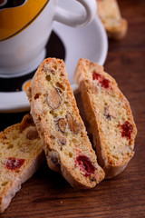 Delicious biscotti cookies with dried cherries and hazelnuts with black tea and white cup. Organic style. White cup of tea.