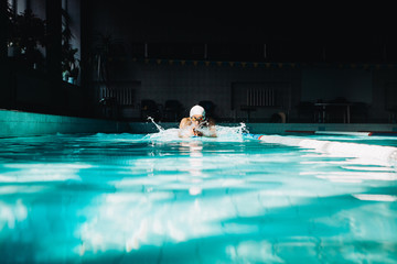 Professional woman swimmer swim using breaststroke technique on the dark background