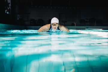 Professional woman swimmer swim using breaststroke technique on the dark background