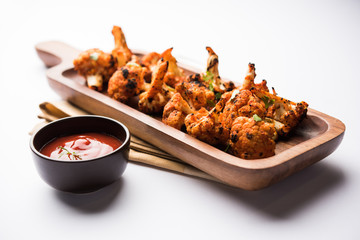 Tandoori Gobi / Roasted cauliflower Tikka is a dry dish made by roasting Cauliflowers in Oven/Tandoor. It's  popular starter food from India. served with ketchup. selective focus