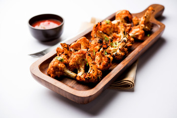 Tandoori Gobi / Roasted cauliflower Tikka is a dry dish made by roasting Cauliflowers in Oven/Tandoor. It's  popular starter food from India. served with ketchup. selective focus