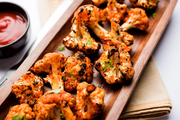 Tandoori Gobi / Roasted cauliflower Tikka is a dry dish made by roasting Cauliflowers in Oven/Tandoor. It's  popular starter food from India. served with ketchup. selective focus