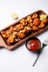 Tandoori Gobi / Roasted cauliflower Tikka is a dry dish made by roasting Cauliflowers in Oven/Tandoor. It's  popular starter food from India. served with ketchup. selective focus
