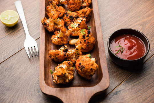 Tandoori Gobi / Roasted cauliflower Tikka is a dry dish made by roasting Cauliflowers in Oven/Tandoor. It's  popular starter food from India. served with ketchup. selective focus