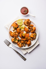 Tandoori Gobi / Roasted cauliflower Tikka is a dry dish made by roasting Cauliflowers in Oven/Tandoor. It's  popular starter food from India. served with ketchup. selective focus