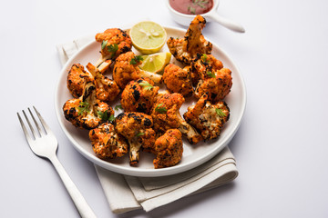 Tandoori Gobi / Roasted cauliflower Tikka is a dry dish made by roasting Cauliflowers in Oven/Tandoor. It's  popular starter food from India. served with ketchup. selective focus