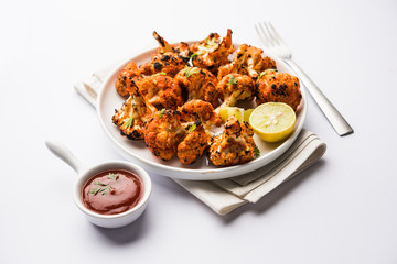 Tandoori Gobi / Roasted cauliflower Tikka is a dry dish made by roasting Cauliflowers in Oven/Tandoor. It's  popular starter food from India. served with ketchup. selective focus