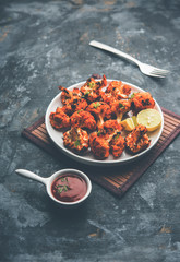 Tandoori Gobi / Roasted cauliflower Tikka is a dry dish made by roasting Cauliflowers in Oven/Tandoor. It's  popular starter food from India. served with ketchup. selective focus
