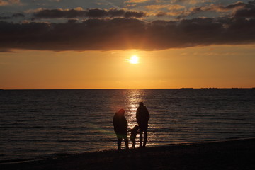 Fototapeta na wymiar silhouettes d'une famille sur la plage au coucher du soleil
