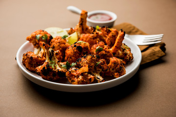 Tandoori Gobi / Roasted cauliflower Tikka is a dry dish made by roasting Cauliflowers in Oven/Tandoor. It's  popular starter food from India. served with ketchup. selective focus