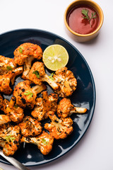 Tandoori Gobi / Roasted cauliflower Tikka is a dry dish made by roasting Cauliflowers in Oven/Tandoor. It's  popular starter food from India. served with ketchup. selective focus